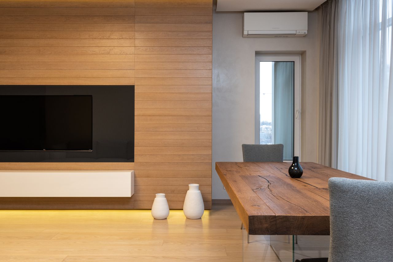 core-values Modern TV set on wooden wall in spacious living room with table and decorated with lights and ceramic vases