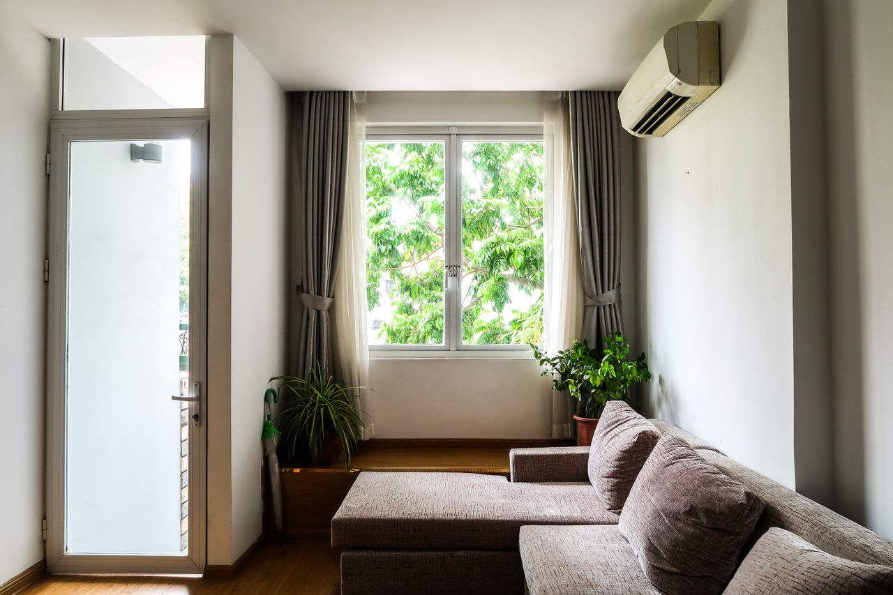 our-mission Bright living room with a cozy sofa, indoor plants, and a large window with curtains.