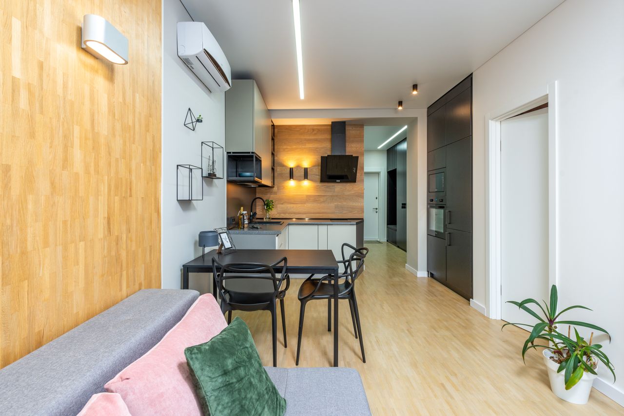 The Art of Drawing Readers In: Your attractive post title goes here Comfortable sofa with cushions placed near table at kitchen with modern appliances in spacious flat with flowerpot and long corridor